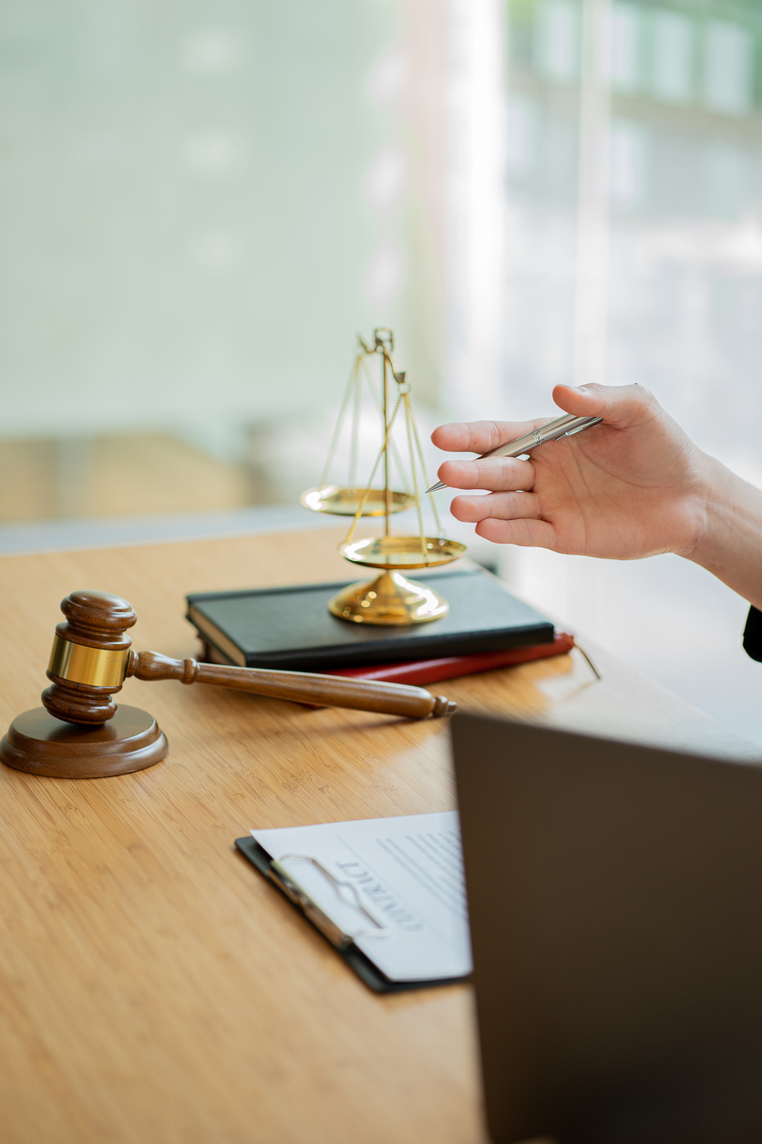 Lawyer working on contract documents and golden goddess scales with hammer on table providing advice, justice and legal counsel office concept images.
