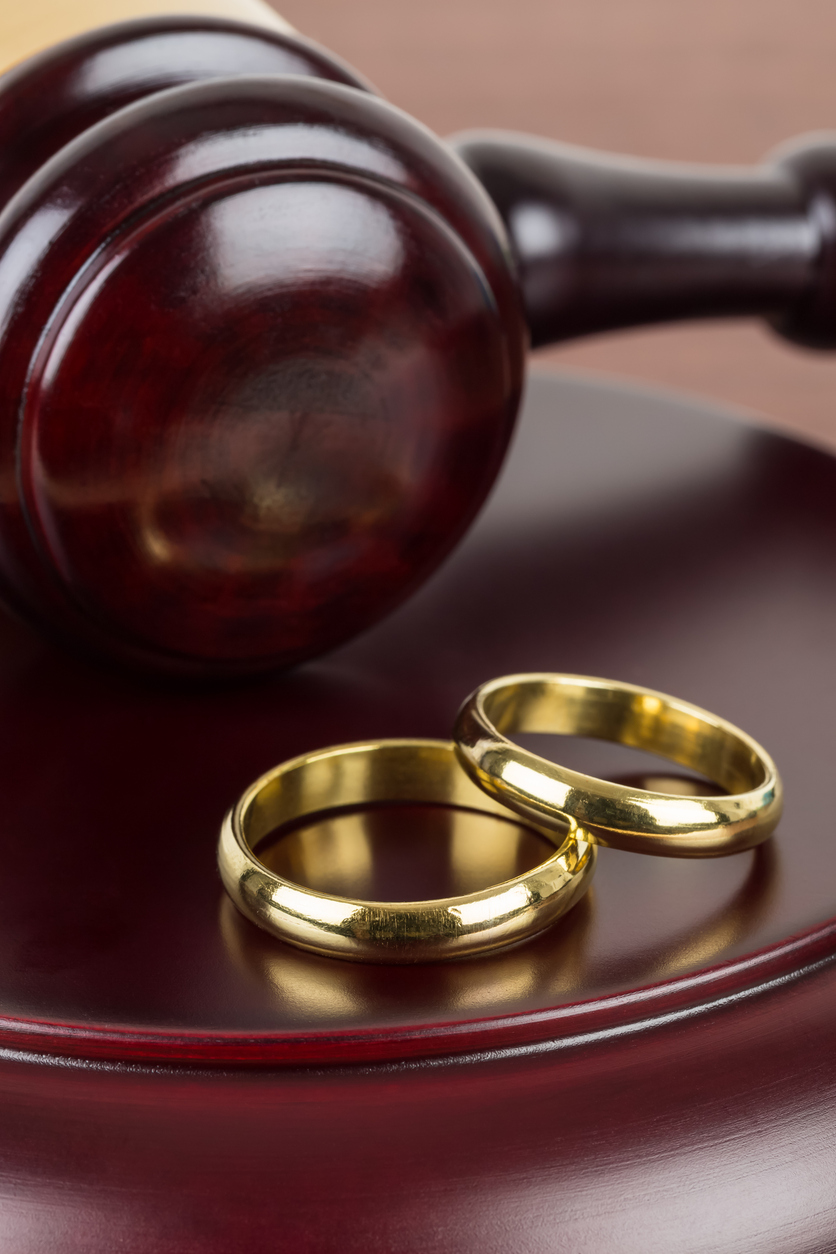 Wooden judge gavel and golden rings divorce concept
